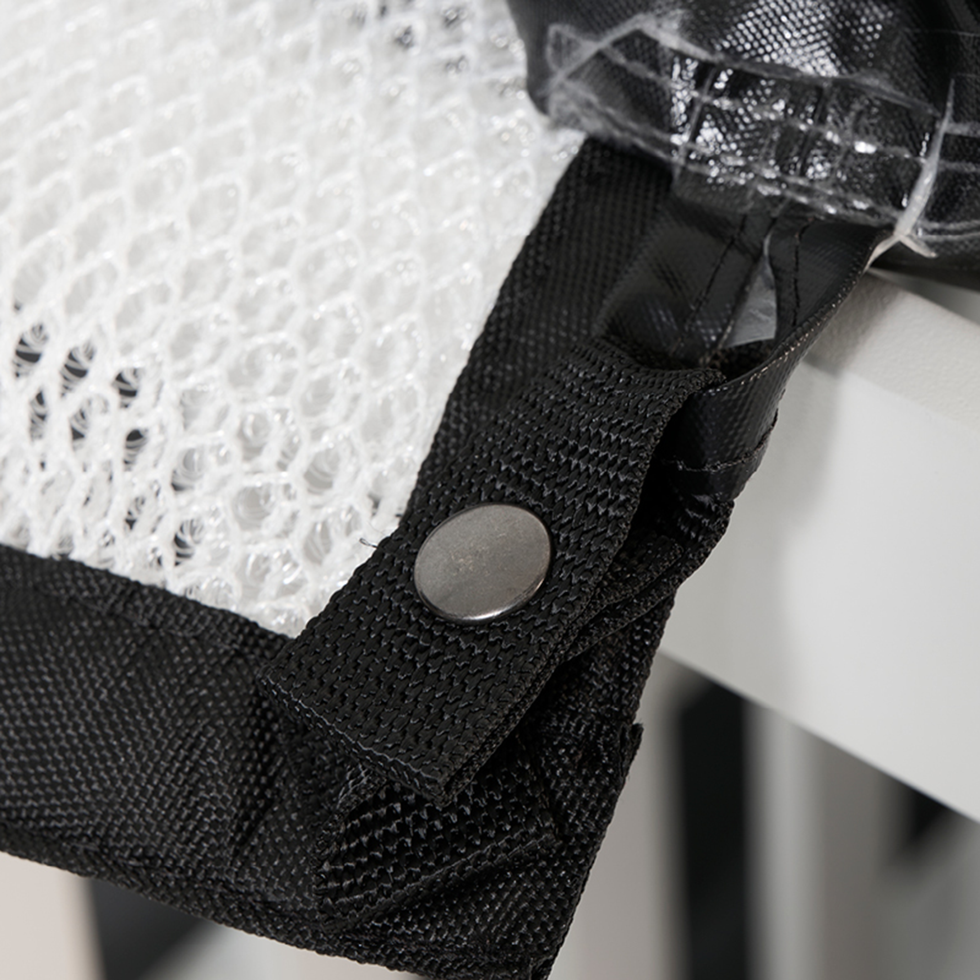 Close-up of DryTop Protect attachment strap with button fastening, securing the breathable mesh layer to outdoor furniture frame.